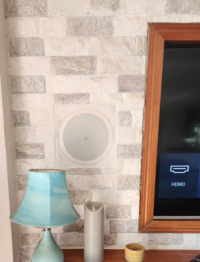 Speaker built flush into a natural stone feature wall beside the TV