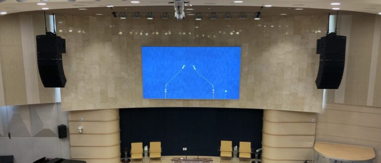 Line array speakers either side of the screen in a church auditorium
